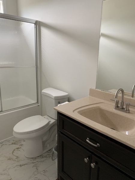 full bathroom with shower / bath combination with glass door, vanity, and toilet