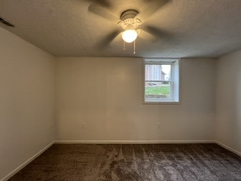 carpeted spare room with a textured ceiling and ceiling fan