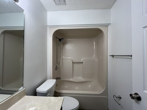 full bathroom with vanity, shower / washtub combination, a textured ceiling, and toilet