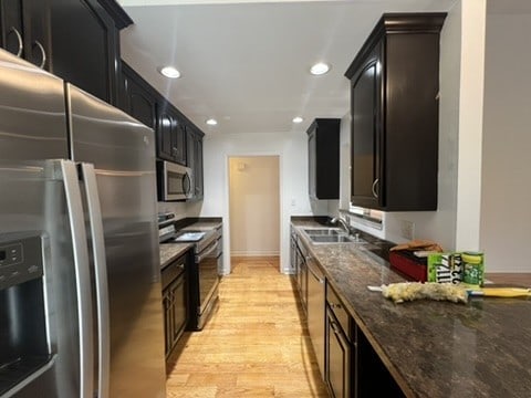 kitchen with dark stone counters, light hardwood / wood-style floors, sink, and appliances with stainless steel finishes