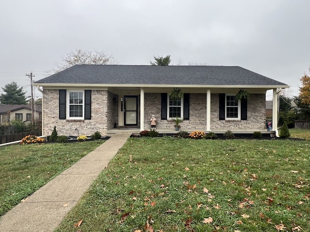 ranch-style home featuring covered porch and a front lawn