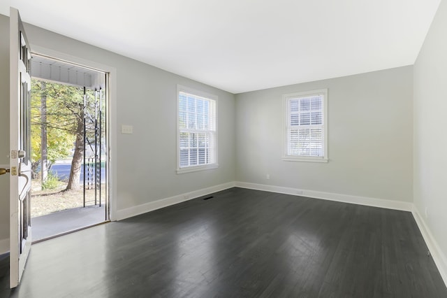 unfurnished room featuring dark wood-type flooring and a healthy amount of sunlight