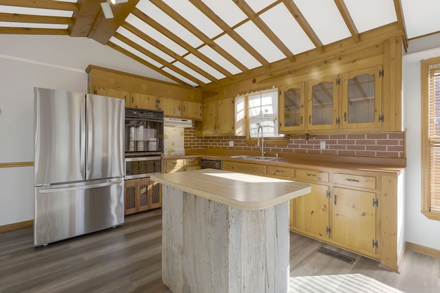 kitchen featuring a center island, sink, vaulted ceiling with beams, decorative backsplash, and black appliances