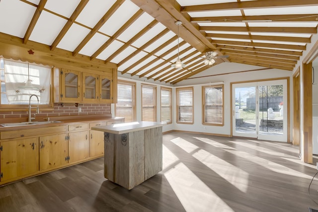 kitchen with lofted ceiling with beams, hardwood / wood-style flooring, a kitchen island, and sink