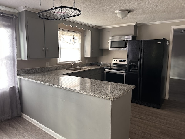 kitchen featuring kitchen peninsula, appliances with stainless steel finishes, pendant lighting, gray cabinets, and dark hardwood / wood-style floors