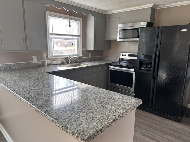 kitchen with stainless steel appliances, kitchen peninsula, a textured ceiling, gray cabinets, and light wood-type flooring