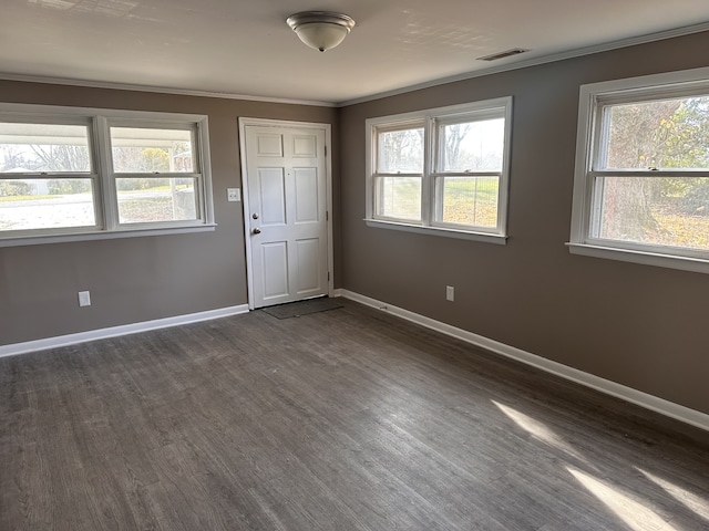 empty room with dark hardwood / wood-style flooring, plenty of natural light, and ornamental molding