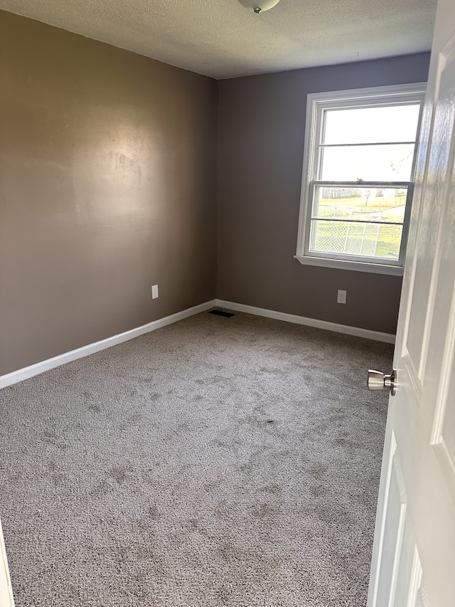 carpeted spare room with a textured ceiling