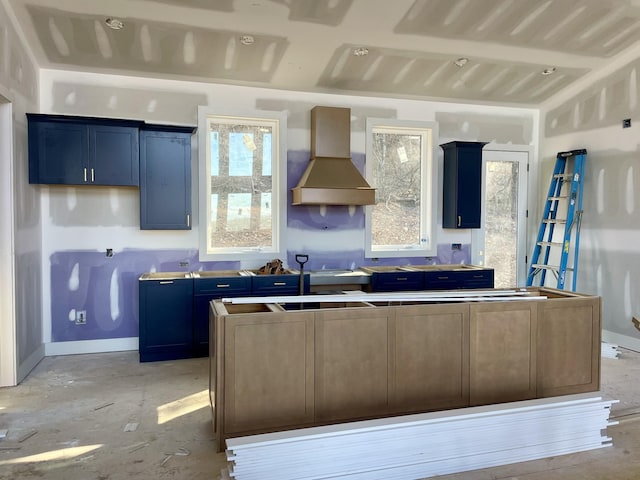 kitchen with a healthy amount of sunlight, a kitchen island, and custom range hood