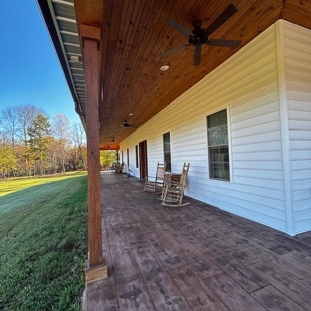 wooden terrace with ceiling fan and a lawn