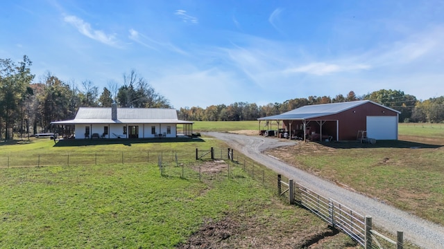 single story home with a front lawn, an outbuilding, and a rural view