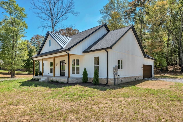 view of side of home featuring a lawn, covered porch, and a garage