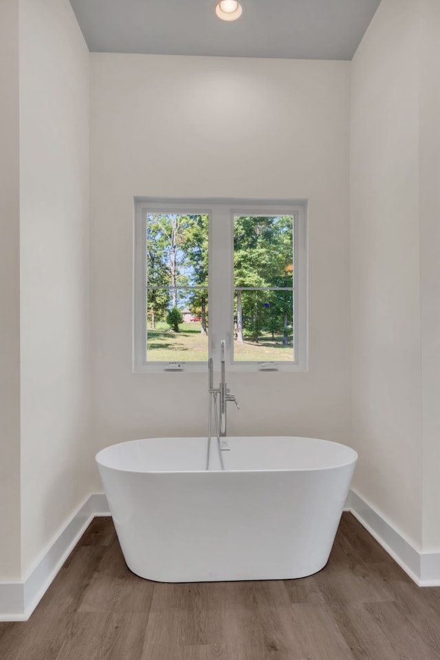 bathroom with hardwood / wood-style flooring and a washtub