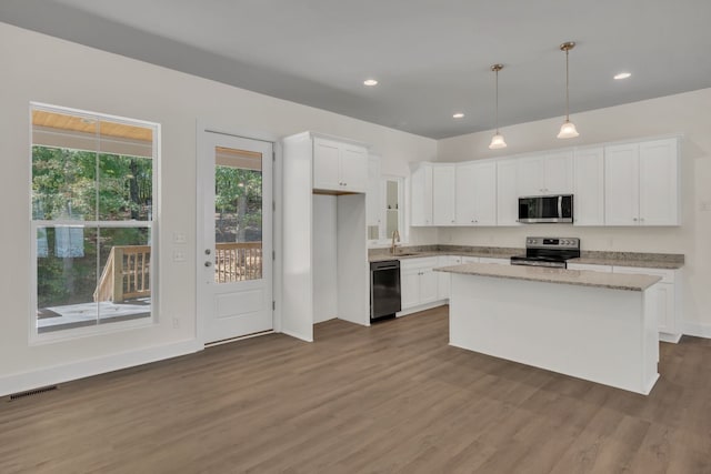 kitchen with dark wood-type flooring, a center island, white cabinets, sink, and appliances with stainless steel finishes