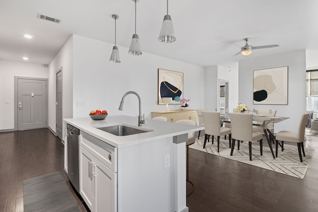 kitchen with white cabinets, sink, stainless steel dishwasher, dark hardwood / wood-style floors, and pendant lighting