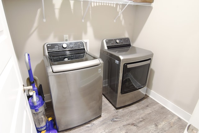 clothes washing area featuring separate washer and dryer and light hardwood / wood-style flooring