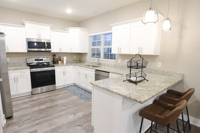 kitchen featuring white cabinets, decorative light fixtures, sink, and appliances with stainless steel finishes