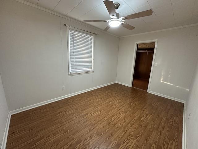 unfurnished bedroom with a closet, a spacious closet, ornamental molding, dark hardwood / wood-style floors, and ceiling fan