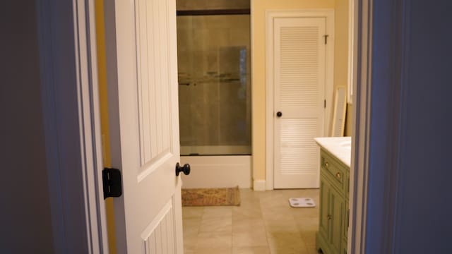 bathroom featuring tile patterned flooring, enclosed tub / shower combo, and vanity