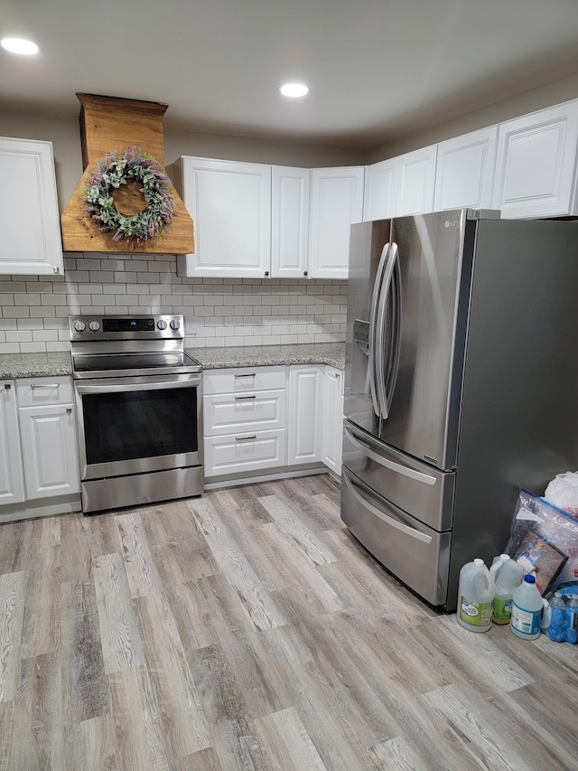 kitchen with tasteful backsplash, white cabinetry, appliances with stainless steel finishes, and custom exhaust hood