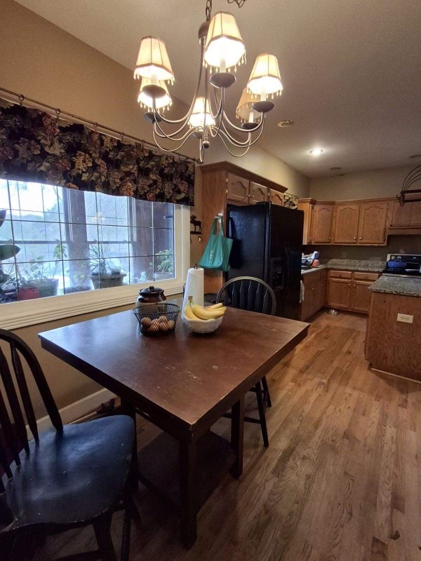 dining room with wood-type flooring, a healthy amount of sunlight, and a chandelier