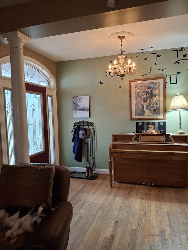 entrance foyer featuring ornate columns, light hardwood / wood-style floors, and a chandelier