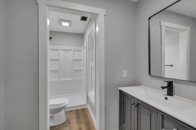 bathroom featuring a shower, hardwood / wood-style floors, vanity, and toilet