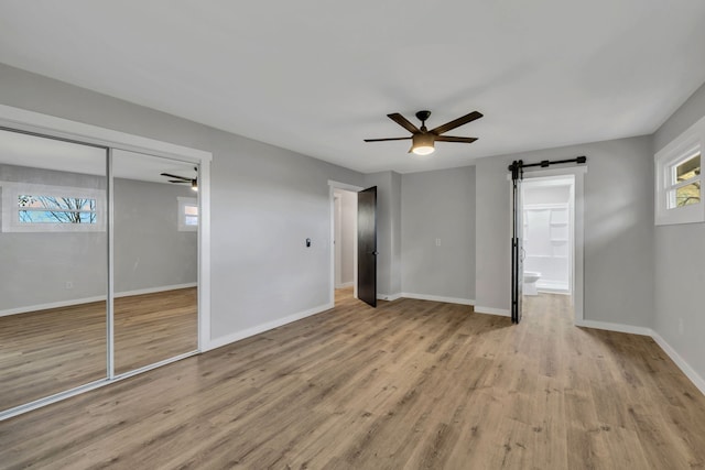 unfurnished bedroom with a closet, light hardwood / wood-style floors, ceiling fan, and ensuite bathroom