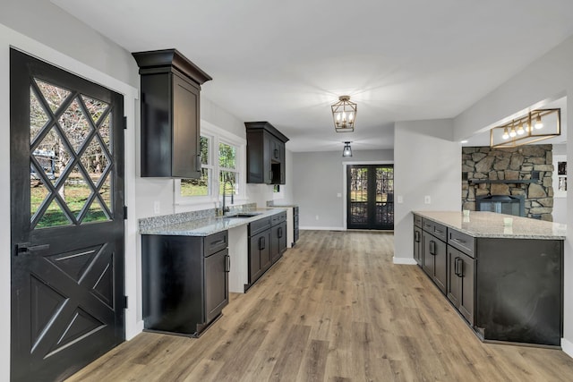 kitchen with light stone countertops, light wood-type flooring, a healthy amount of sunlight, and sink