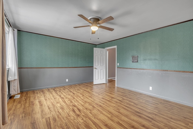 empty room with crown molding, ceiling fan, and light wood-type flooring