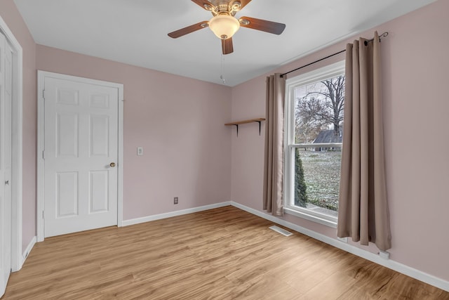 empty room with ceiling fan, plenty of natural light, and light wood-type flooring