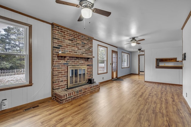 unfurnished living room featuring ornamental molding, a brick fireplace, and light hardwood / wood-style floors