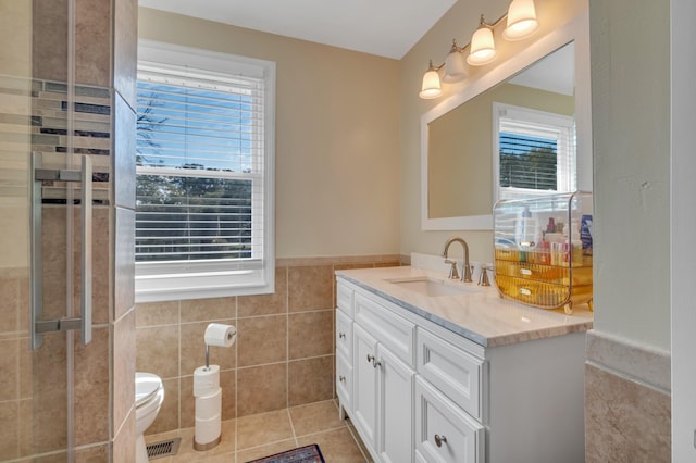 bathroom featuring tile patterned floors, toilet, tile walls, and vanity