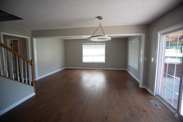 unfurnished dining area with dark wood-type flooring, a textured ceiling, and ceiling fan