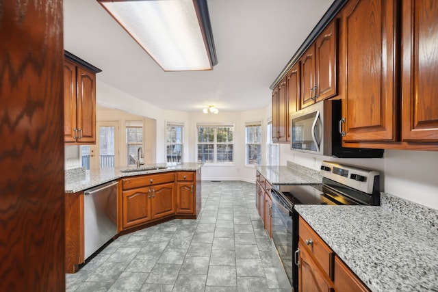 kitchen with light stone countertops, stainless steel appliances, kitchen peninsula, and sink