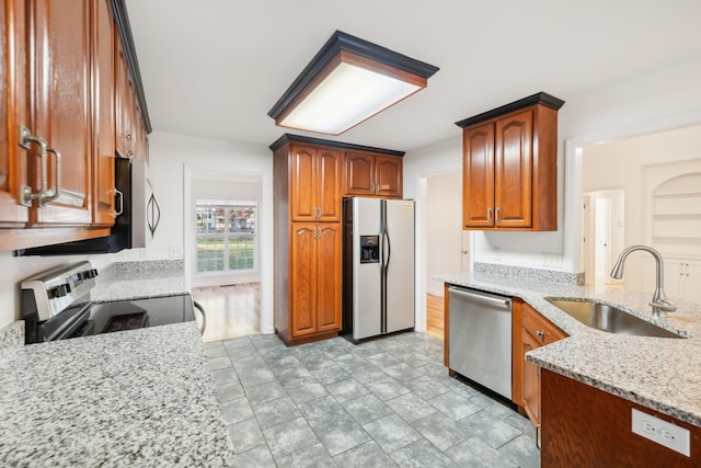 kitchen with light hardwood / wood-style floors, light stone counters, sink, and appliances with stainless steel finishes