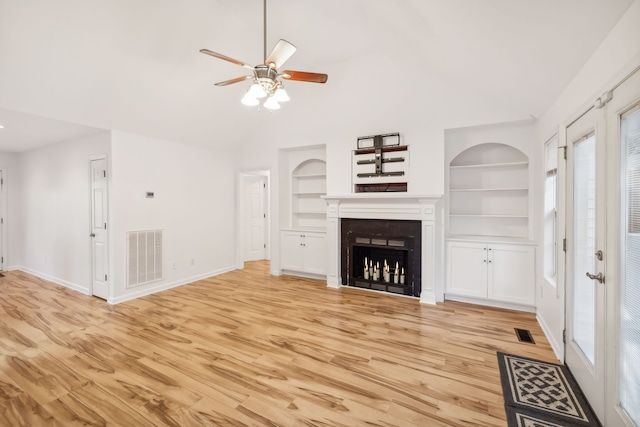 unfurnished living room featuring light wood-type flooring, built in features, ceiling fan, and a healthy amount of sunlight