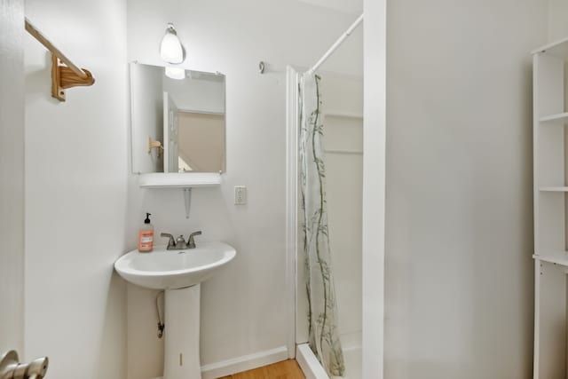 bathroom with hardwood / wood-style flooring, walk in shower, and sink