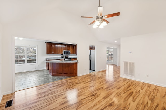 kitchen featuring stainless steel appliances, ceiling fan, sink, high vaulted ceiling, and light hardwood / wood-style flooring