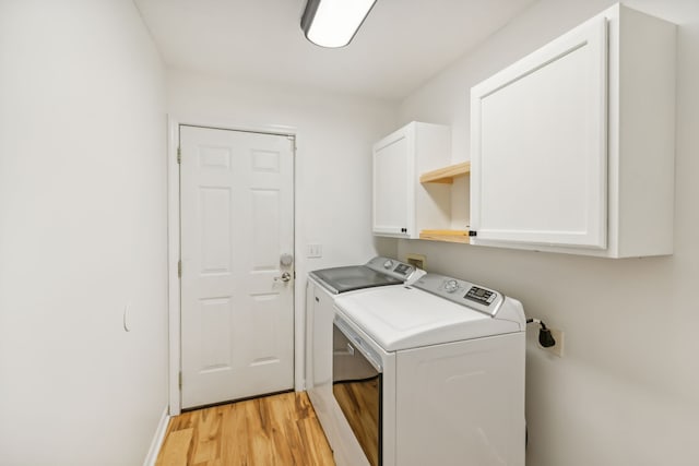 clothes washing area with washing machine and clothes dryer, cabinets, and light hardwood / wood-style floors