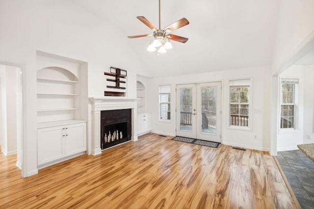 unfurnished living room featuring french doors, light hardwood / wood-style flooring, built in features, and ceiling fan