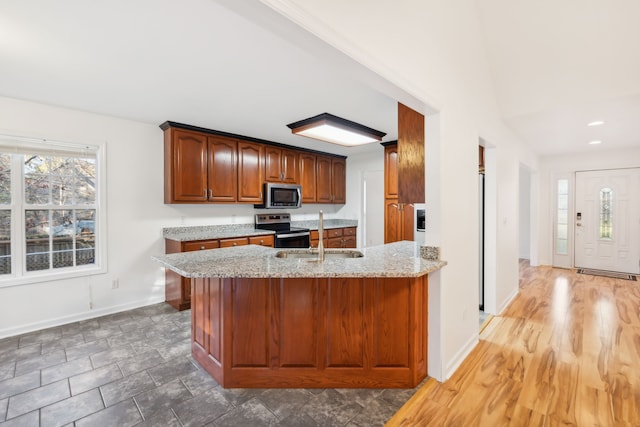 kitchen featuring hardwood / wood-style flooring, light stone countertops, sink, and appliances with stainless steel finishes