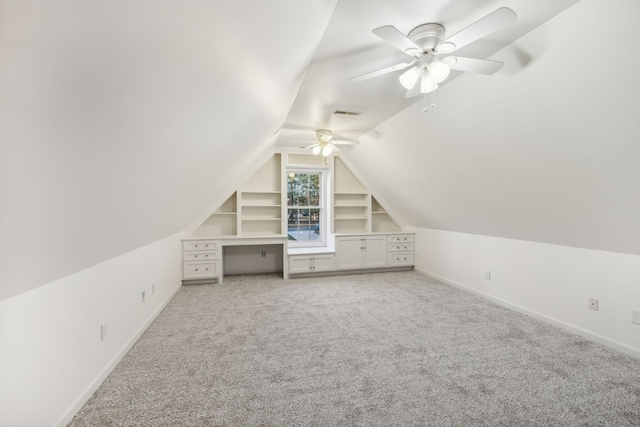 bonus room with ceiling fan, built in features, light carpet, and vaulted ceiling