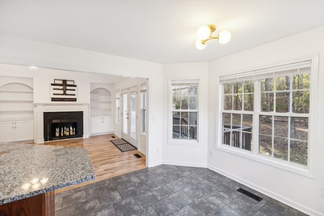 unfurnished living room with a healthy amount of sunlight, dark hardwood / wood-style flooring, and built in features