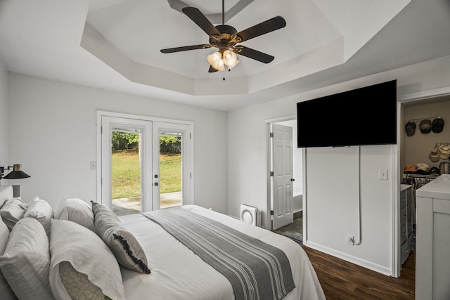 bedroom featuring access to outside, dark hardwood / wood-style floors, a raised ceiling, and ceiling fan