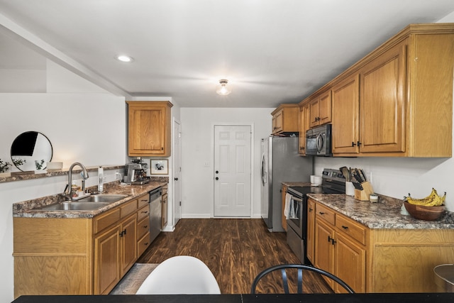 kitchen with dark hardwood / wood-style flooring, dark stone countertops, sink, and appliances with stainless steel finishes