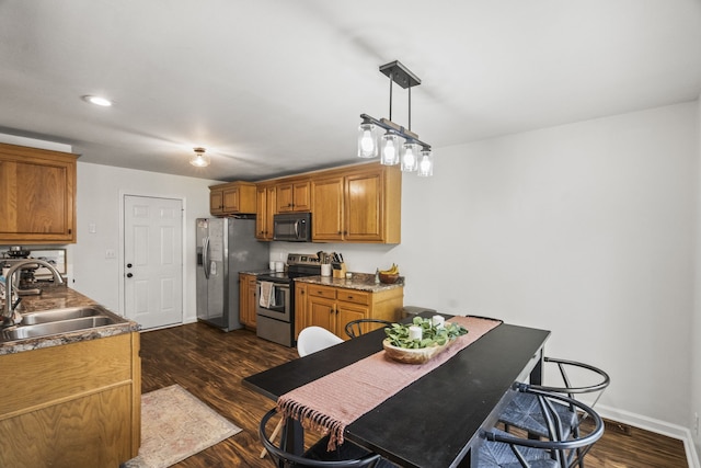 kitchen featuring dark hardwood / wood-style flooring, sink, pendant lighting, and appliances with stainless steel finishes