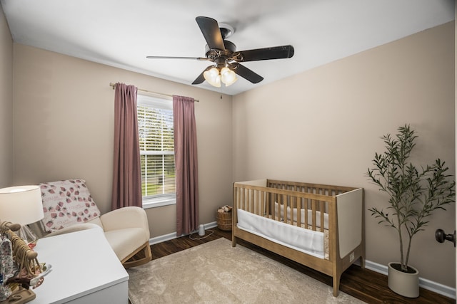 bedroom featuring wood-type flooring, ceiling fan, and a crib