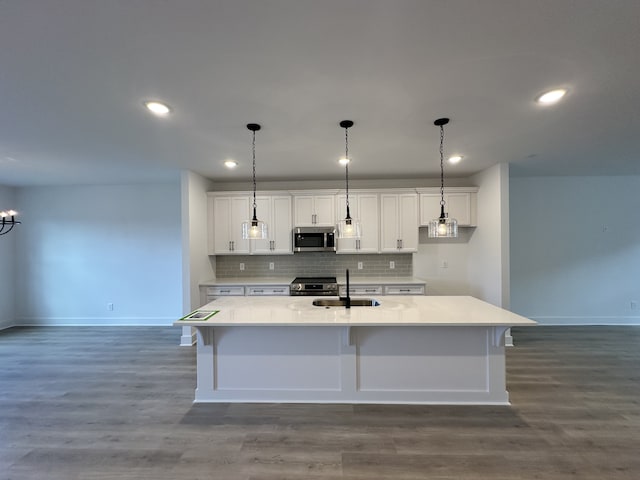 kitchen featuring white cabinetry, appliances with stainless steel finishes, dark hardwood / wood-style flooring, sink, and an island with sink