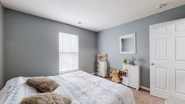 bedroom with a textured ceiling and light colored carpet